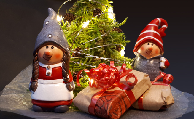 Two small santas with the christmas presents and the christmas tree.